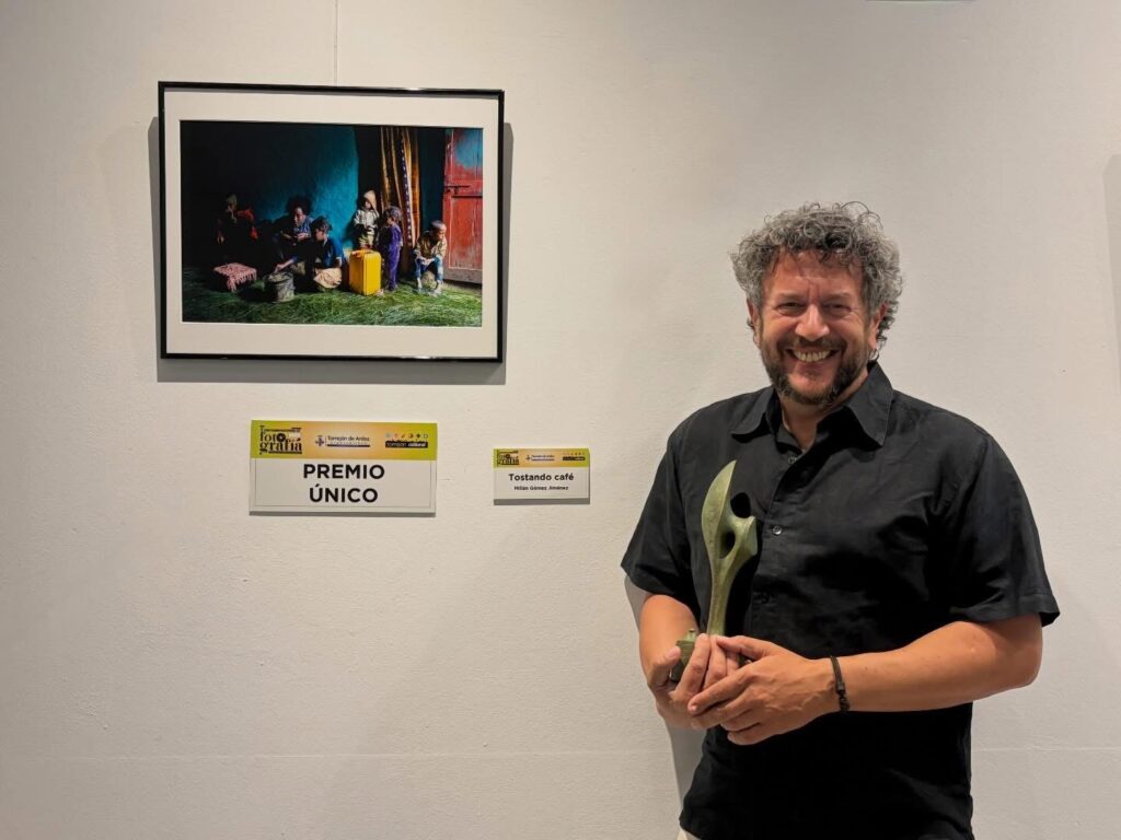 Millán Gómez junto a su fotografía ‘Tostando café’ | Facebook: Millán Gómez